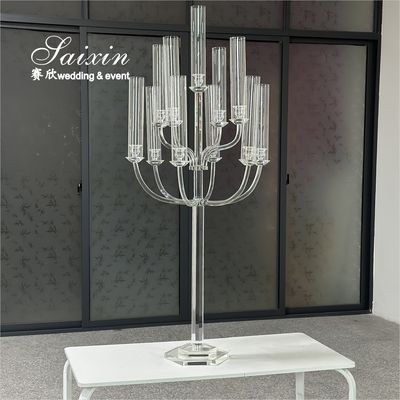 Un magnifique chandelier en verre transparent avec de hauts pots en verre pour les objets principaux du mariage